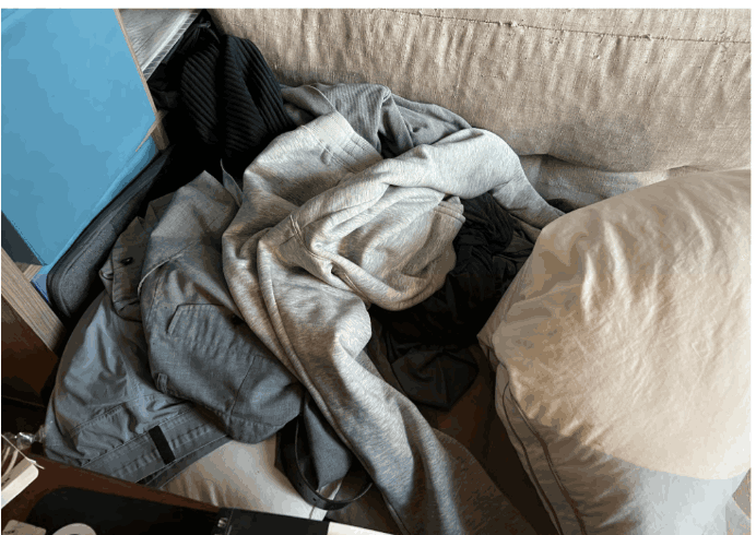 Worn clothes piled at the foot of a bed