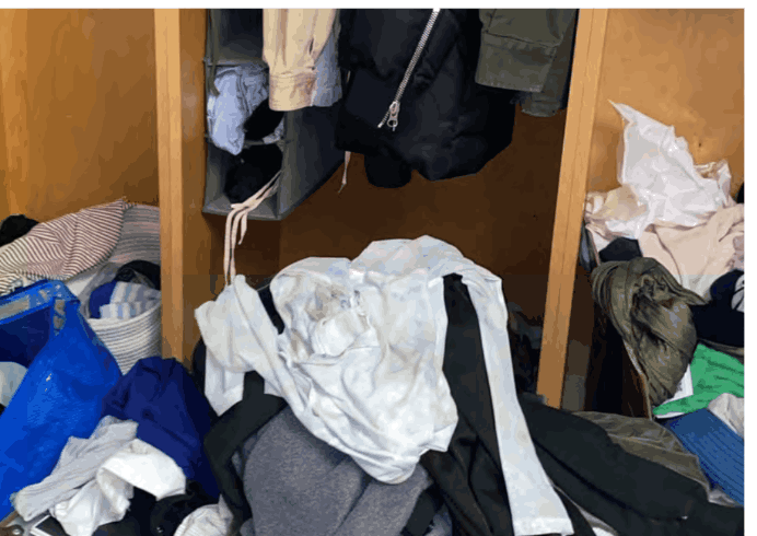 Closet with clothes stacked on shelves, hamper edges, and the floor