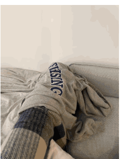 A worn sweatshirt draped over the arm of a sofa