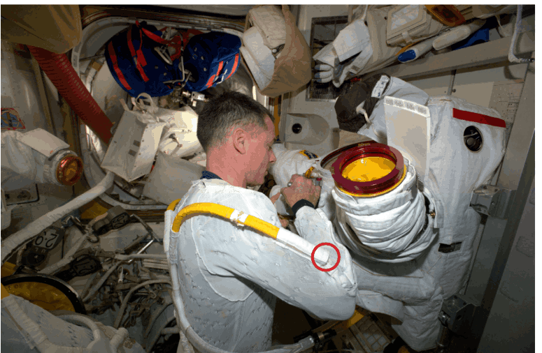 Astronaut donning a spacesuit, with the vent duct visible near the elbow